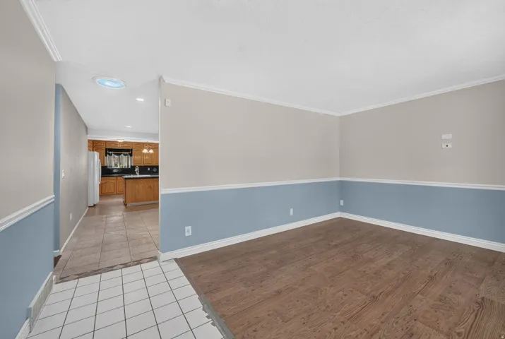 Wood-finish flooring, two-tone wall treatment, crown molding, and white trim