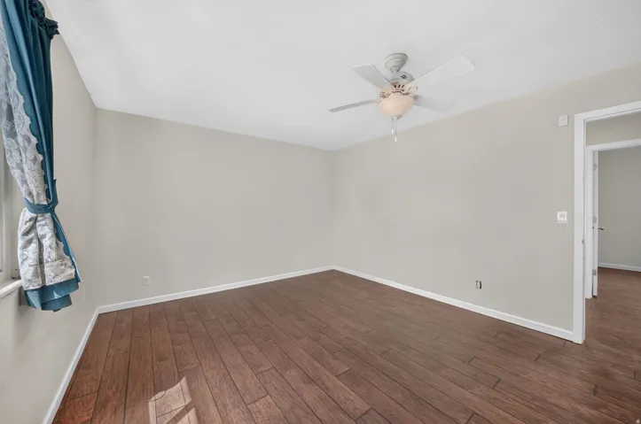 Wood-finish flooring, light neutral wall paint, and a ceiling fan with integrated lighting