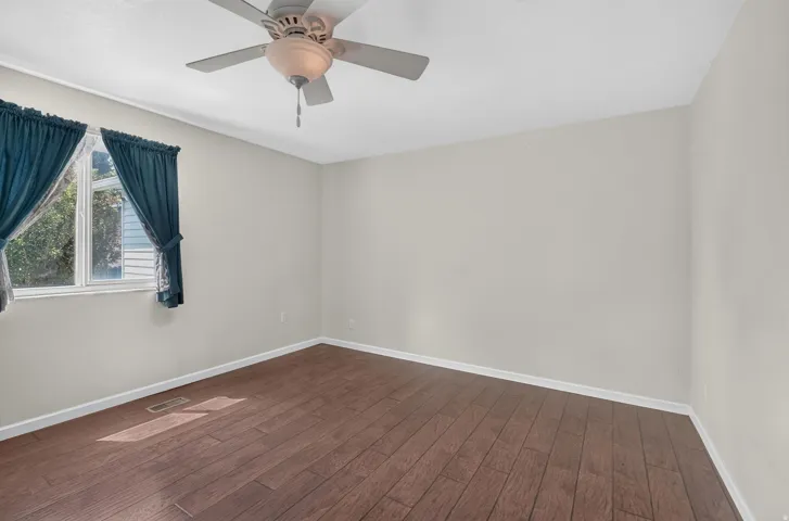 Wood-finish flooring, white trim, and a ceiling fan