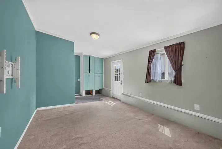 Carpeted room featuring a white paneled door with glass inserts, recessed lighting, and built-in teal cabinetry