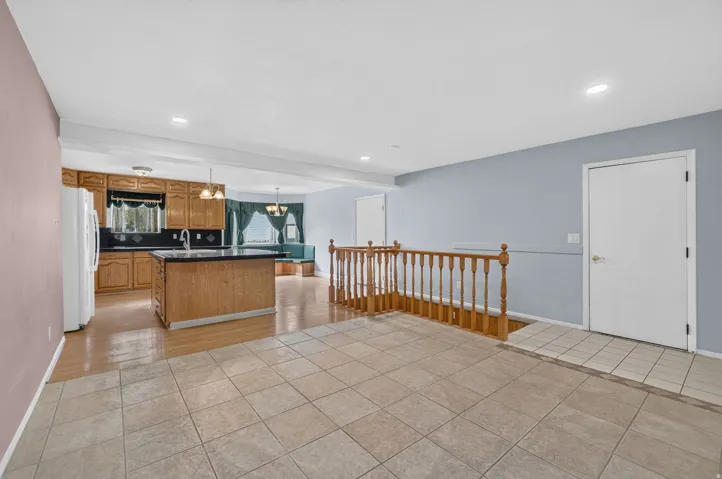 Tile flooring, wood-finish flooring, wood cabinetry, built-in kitchen island, recessed lighting