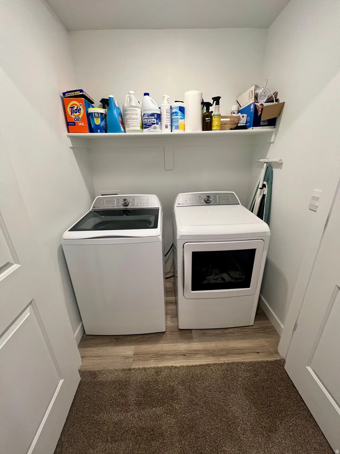 Laundry area featuring a wall-mounted shelf and wood-finish flooring