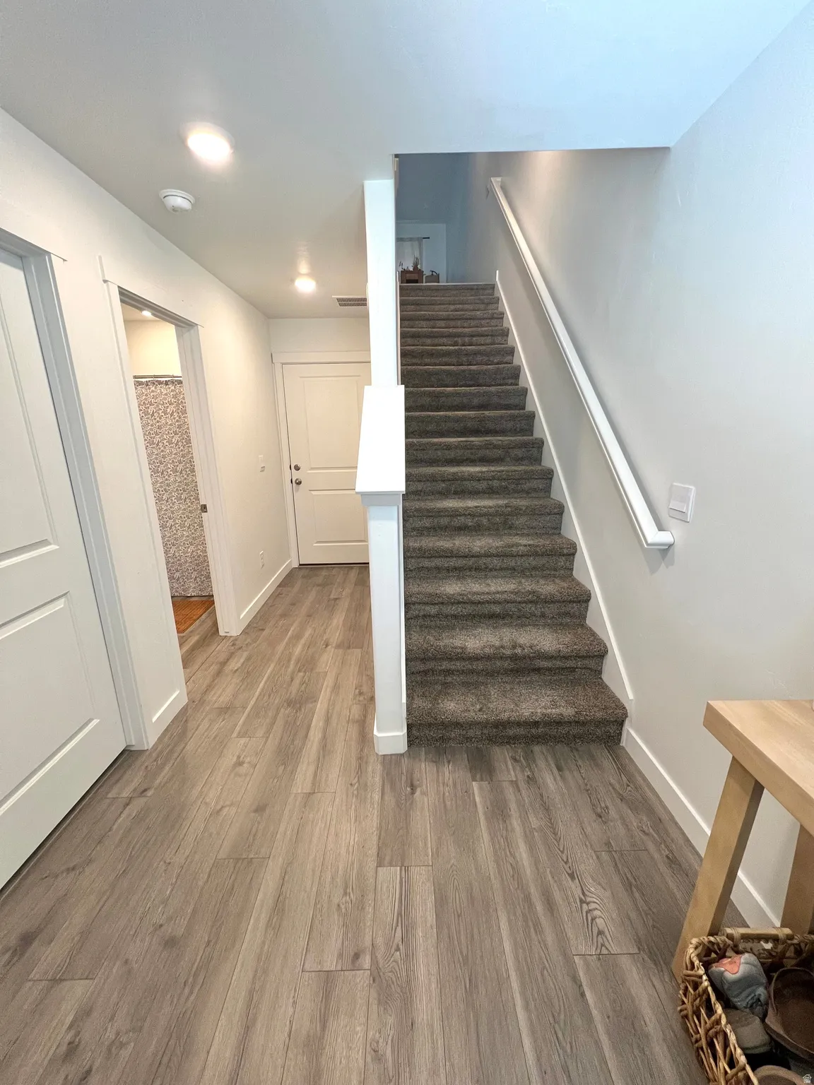 Wood-finish flooring, staircase with carpeted treads, white walls, and recessed lighting