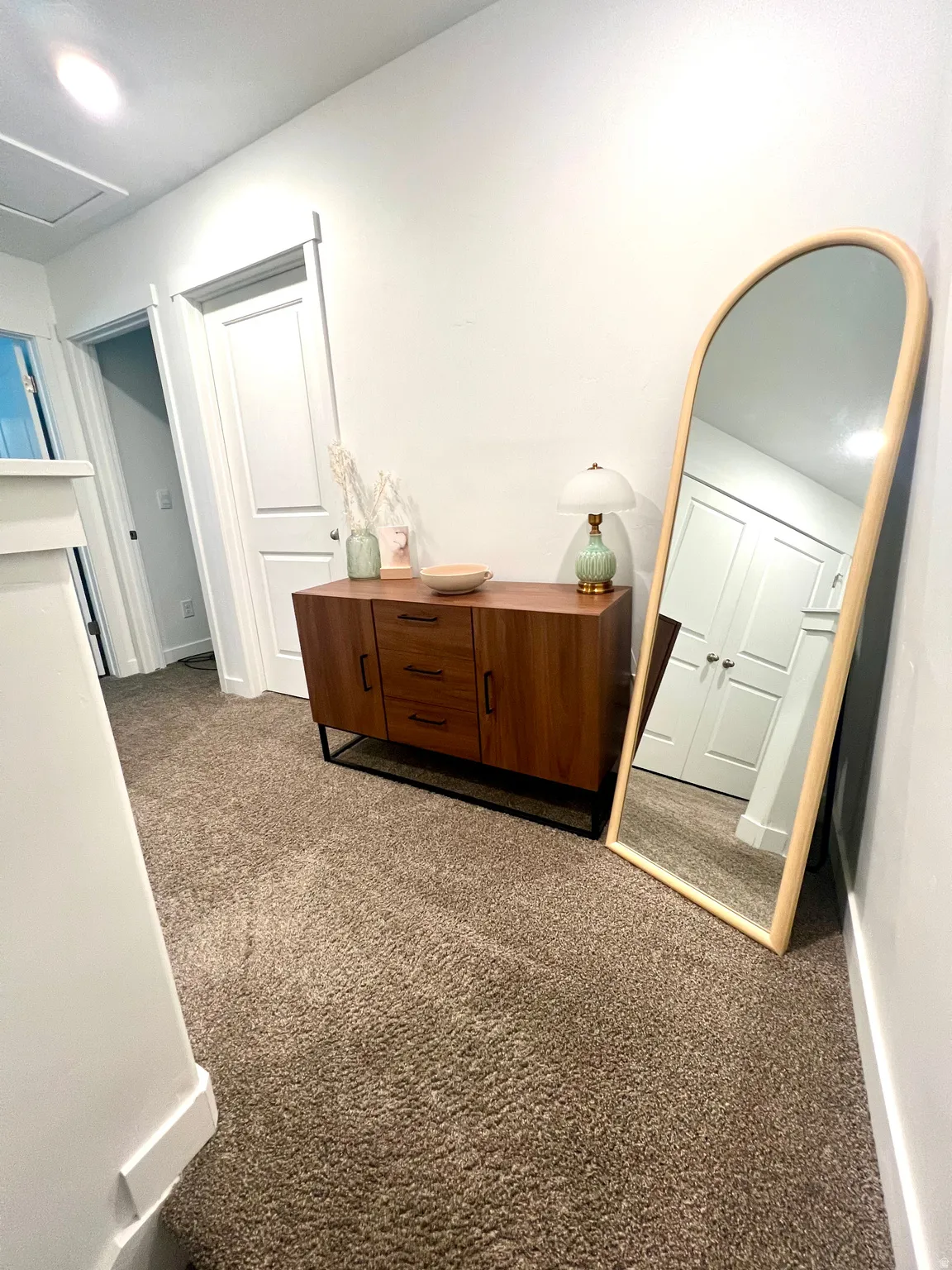 Soft carpet flooring, crisp white walls, and a recessed ceiling light