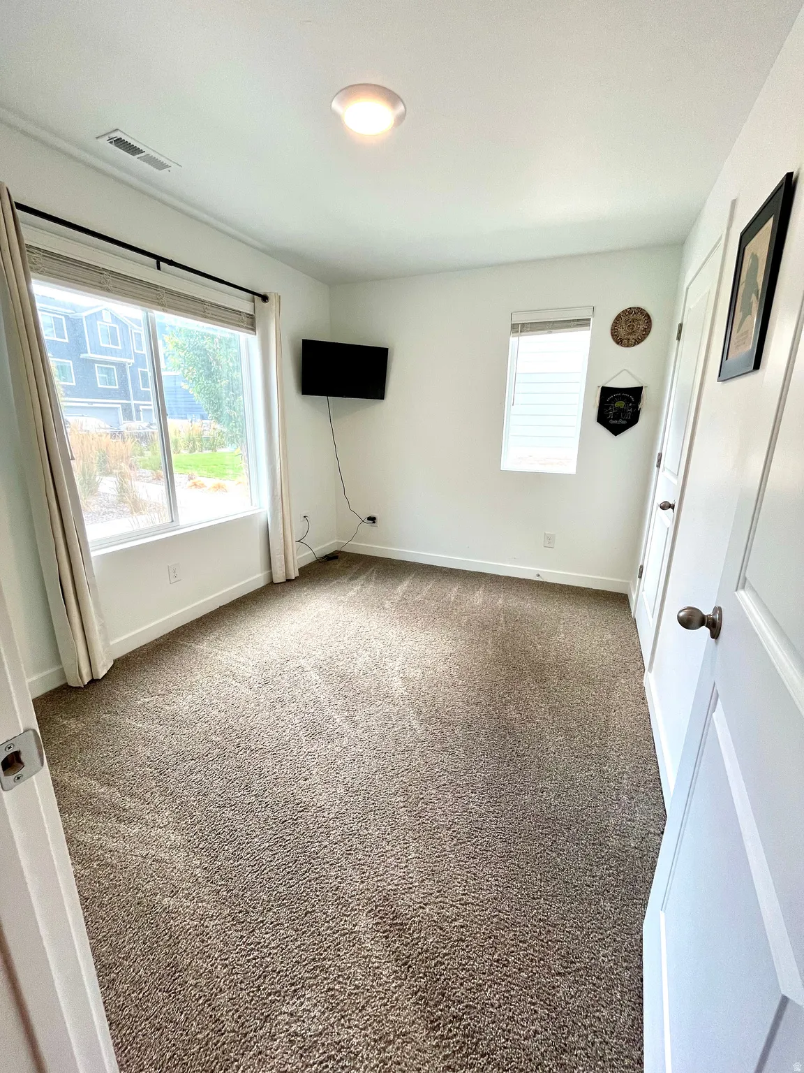 Carpeted flooring, white walls, two windows with window treatments, and a ceiling-mounted light fixture
