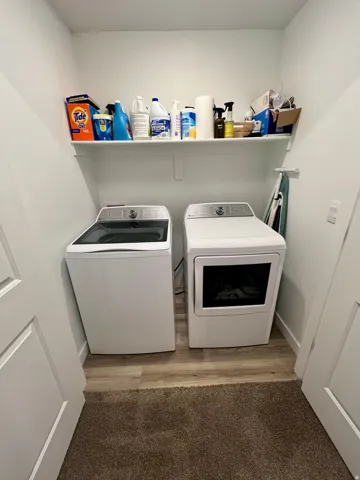 Laundry area featuring a wall-mounted shelf and wood-finish flooring
