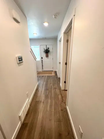 Entryway featuring wood-finish flooring, white walls, recessed lighting, and a white paneled door