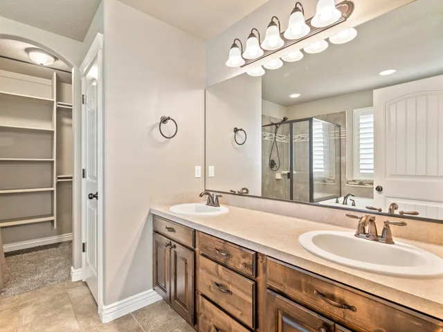 Dual vanity with wood cabinetry, brushed bronze fixtures, and a large wall mirror