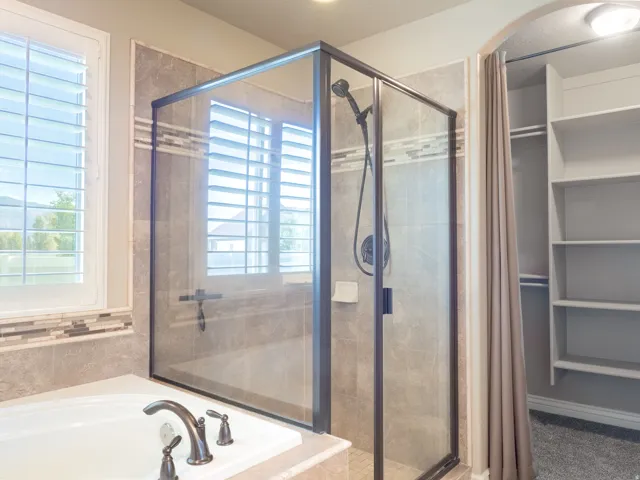 Tiled shower with dark-framed glass enclosure and a handheld shower head