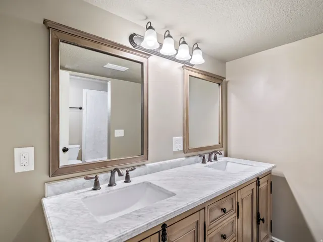 Dual vanity with a stone-finish countertop, undermount sinks, and wood cabinetry