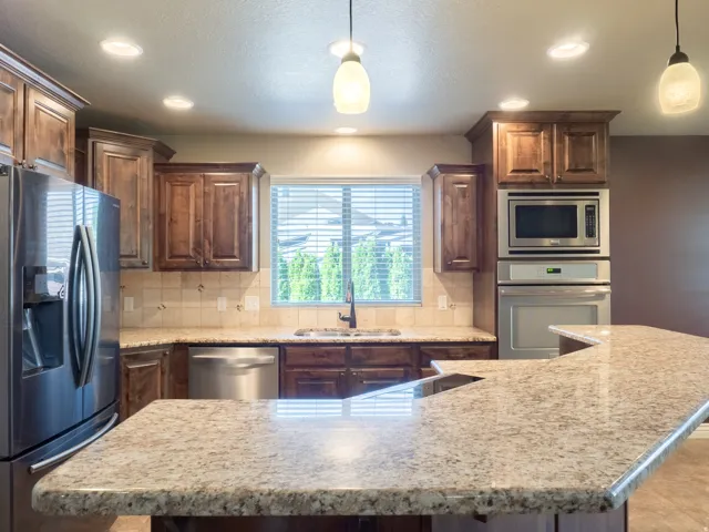 Kitchen featuring wood cabinetry, stainless steel appliances, speckled countertops, and recessed lighting