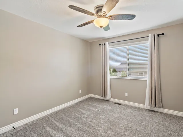 Neutral paint tones, ceiling fan with integrated lighting, window with blinds, and plush carpeting
