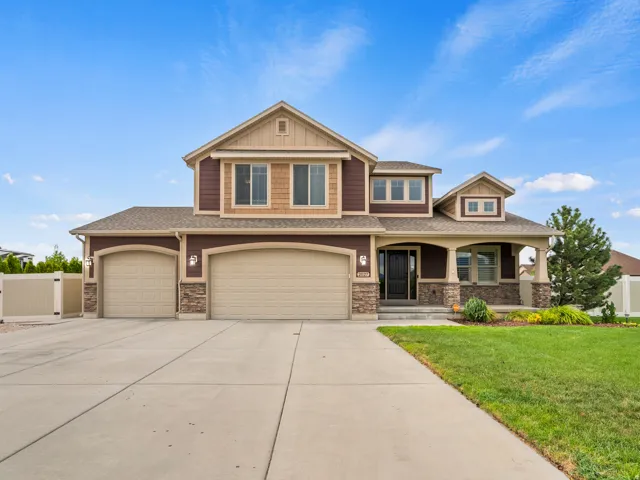 Two-story residence featuring a two-car garage, stone accents, and a covered porch
