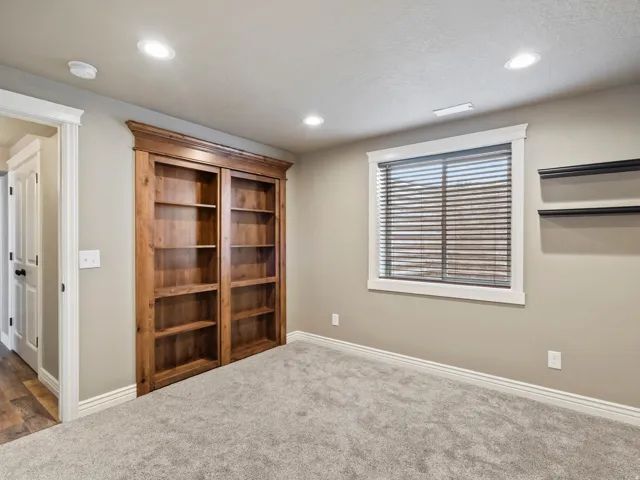 Built-in wood-finish shelving, recessed lighting, and a window with blinds