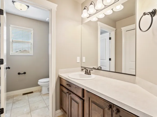 Extended vanity with an integrated sink, broad wall-mounted mirror, and decorative light fixture