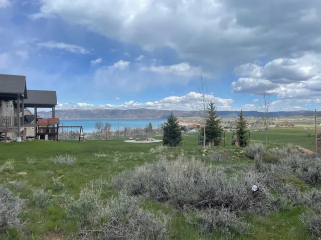 Expansive outdoor space featuring a large grassy lawn, distant lake, and mountain scenery