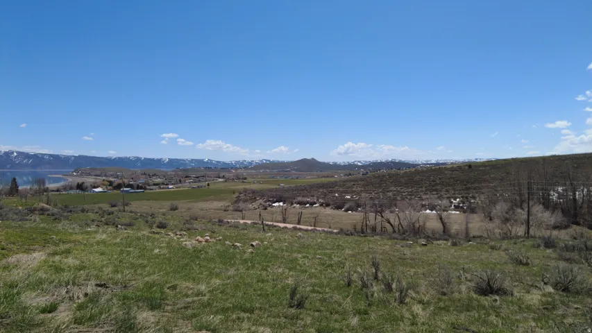 Expansive land parcel with distant water body, mountain range, and verdant fields