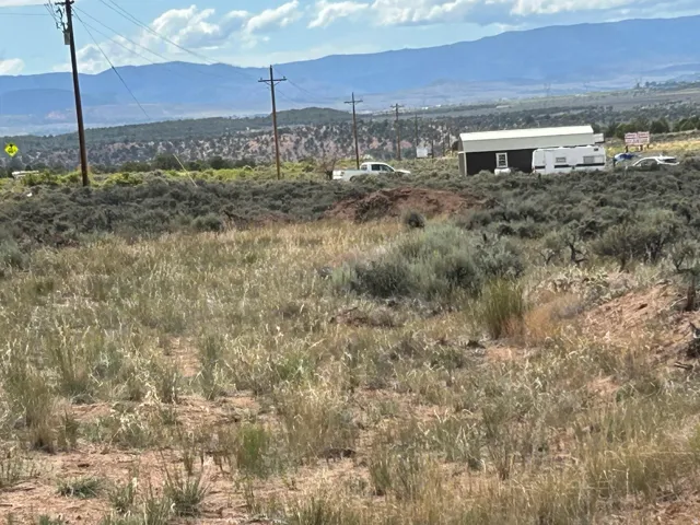 Expansive undeveloped land featuring natural desert vegetation, distant mountains, and utility poles
