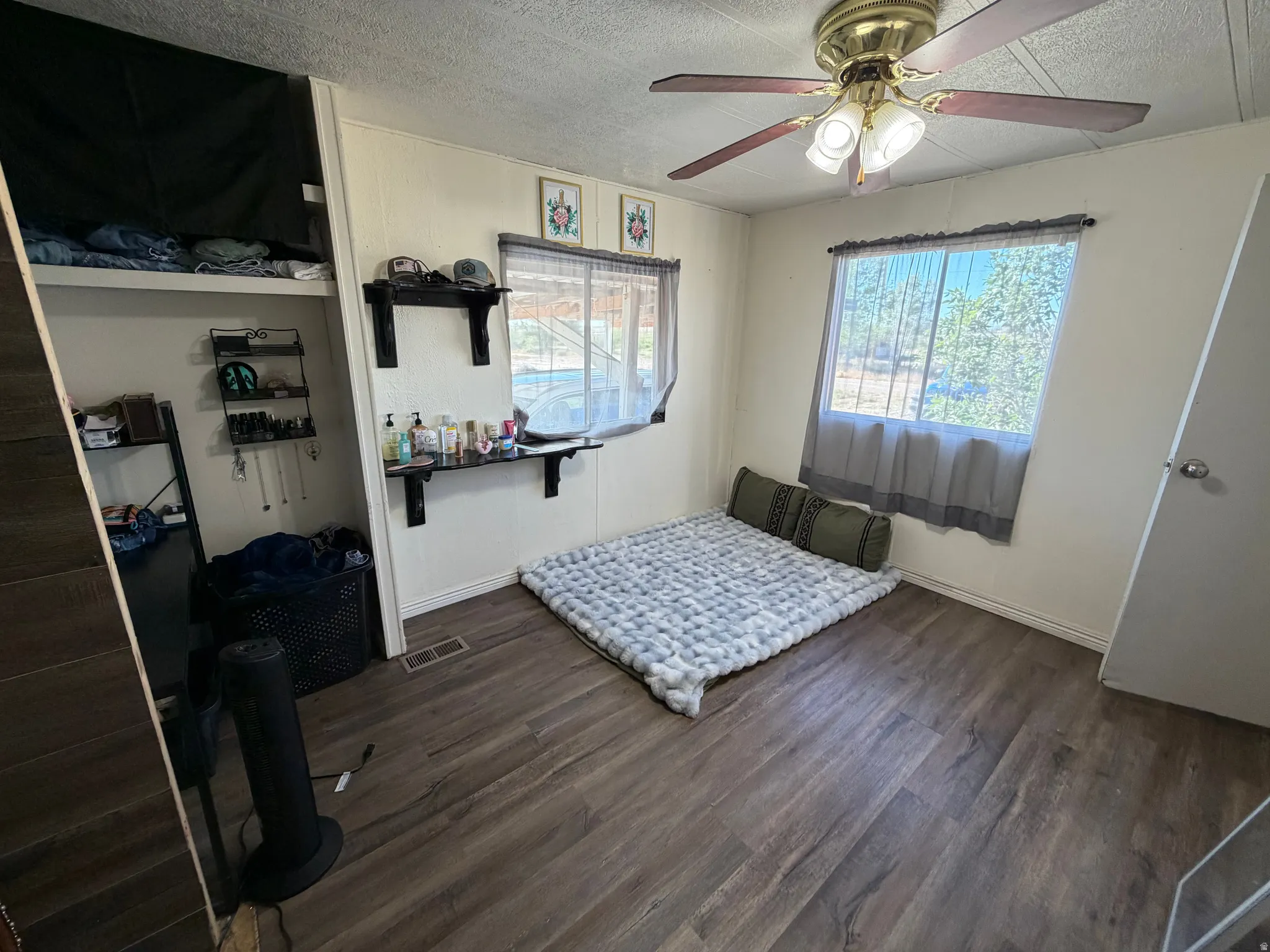 Wood-finish flooring, white paneled walls, two windows, and a ceiling fan with integrated lighting