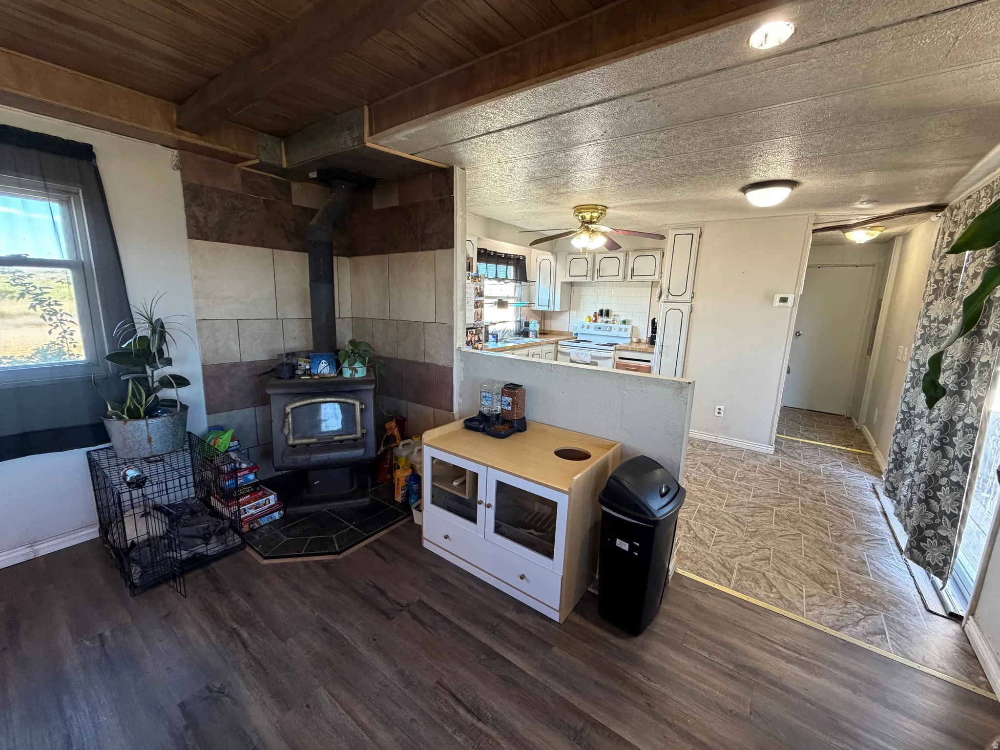 Wood-finish flooring, wood-paneled ceiling, and a corner wood-burning stove with a tiled surround