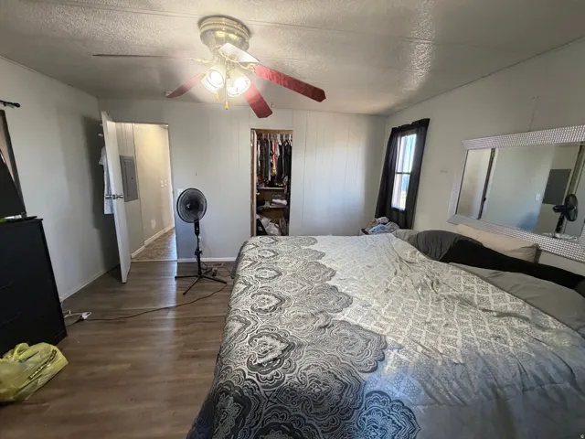 Wood-finish flooring, ceiling fan with integrated lighting, and a built-in closet