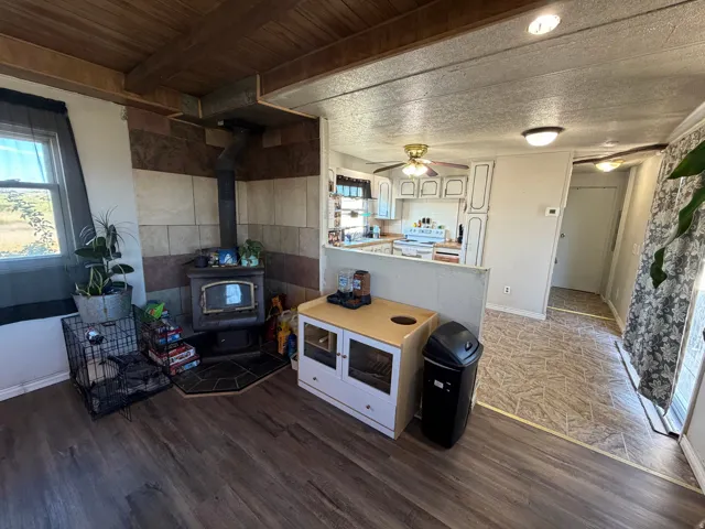 Wood-finish flooring, wood-paneled ceiling, and a corner wood-burning stove with a tiled surround