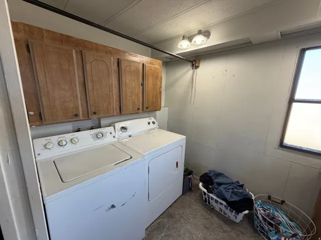 Laundry area featuring overhead wood-finish cabinetry, a window, and overhead lighting