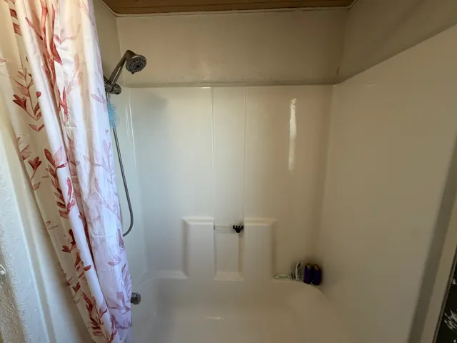 White shower/tub combination with an integrated multi-shelf soap dish and a brushed nickel showerhead