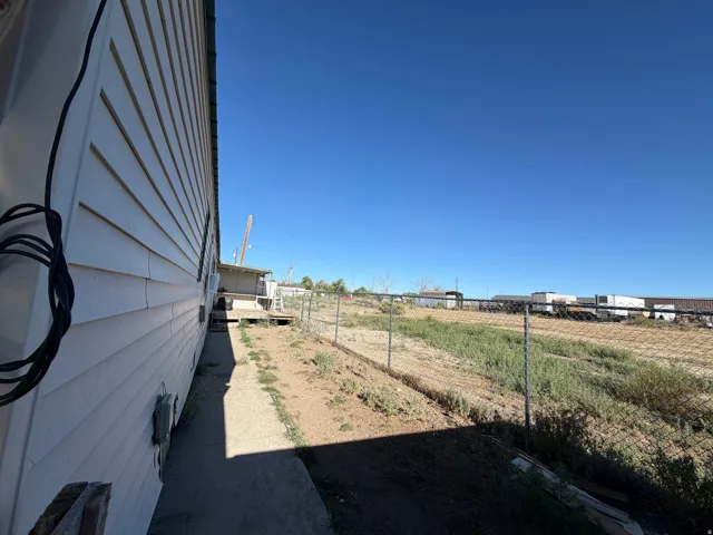 White siding exterior with a chain link fence
