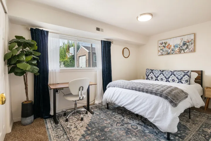 Recessed window with natural light, integrated ceiling light fixture, wood-finish headboard, and carpet flooring