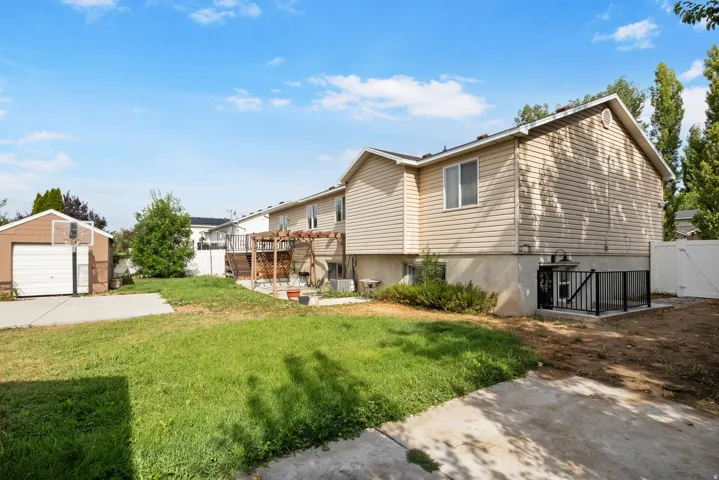 Exterior featuring a detached garage, concrete driveway, wood deck, and a fenced area
