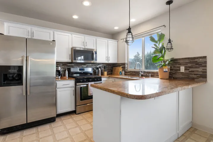Kitchen featuring stainless steel appliances, white cabinetry, granite-finish countertops, a tile backsplash, and recessed lighting
