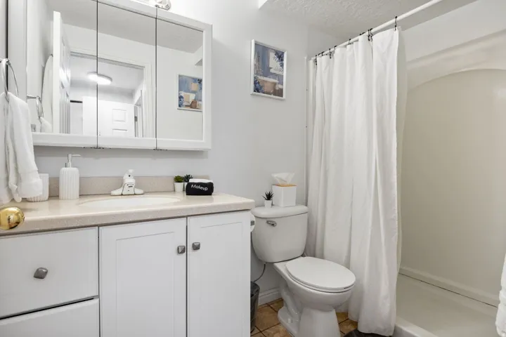 White vanity with a built-in sink, neutral countertop, and a mirrored medicine cabinet