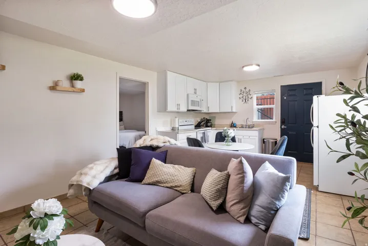 Open-concept living area featuring a kitchen with white cabinetry and a built-in microwave