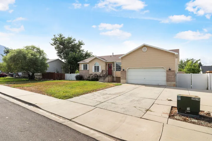 Siding exterior with a two-car garage, concrete driveway, and mature landscaping