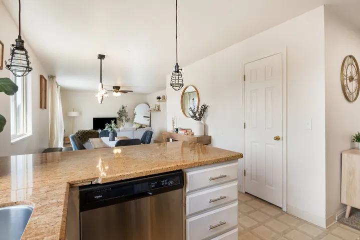 Kitchen island with a granite countertop, undermount sink, and stainless steel dishwasher