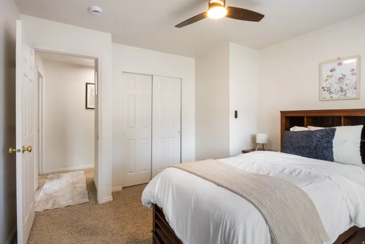 Carpeted flooring, ceiling fan with integrated lighting, and white bi-fold closet doors