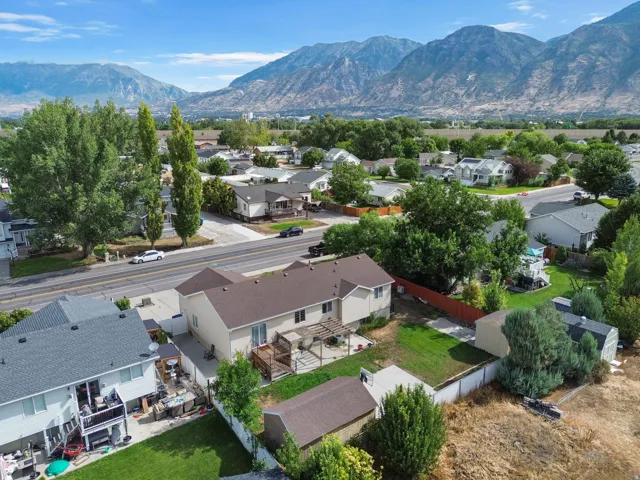Aerial view showcasing a single-story residence with a brown-toned roof, expansive manicured lawn, and mature landscaping throughout the property