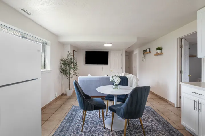 White refrigerator appliance, tiled flooring, white cabinetry, light-toned countertop, recessed lighting