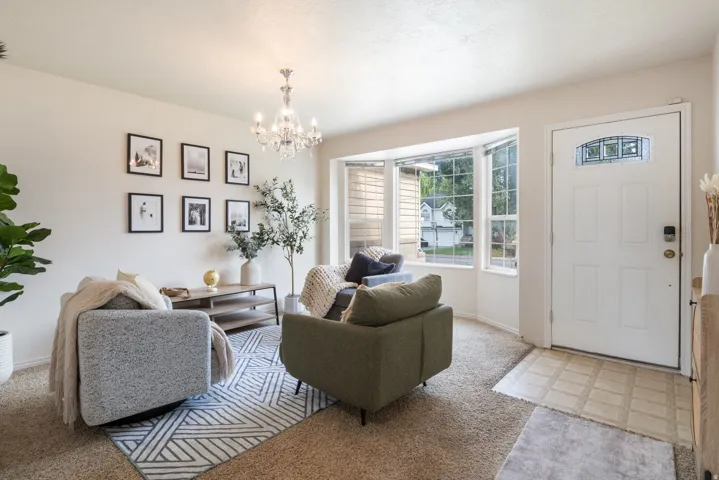 Bay window offering abundant natural light, a white paneled entry door with decorative glass, and a crystal chandelier
