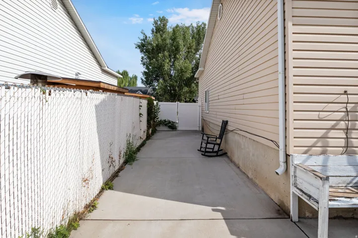 Concrete pathway with a white chain-link fence and vinyl siding