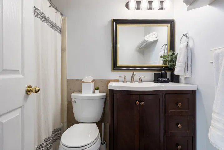 Bathroom featuring a dark wood-finish vanity with an integrated sink, framed mirror, and brushed nickel fixtures