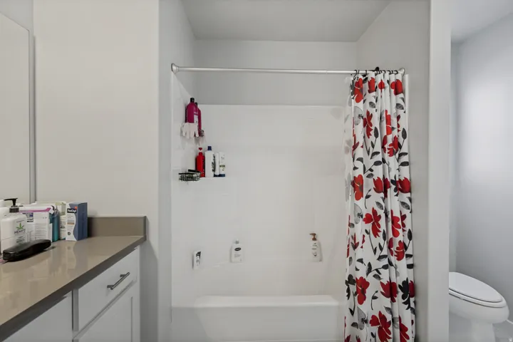 White bathroom featuring a built-in shower/tub combination and a vanity with a light-toned countertop