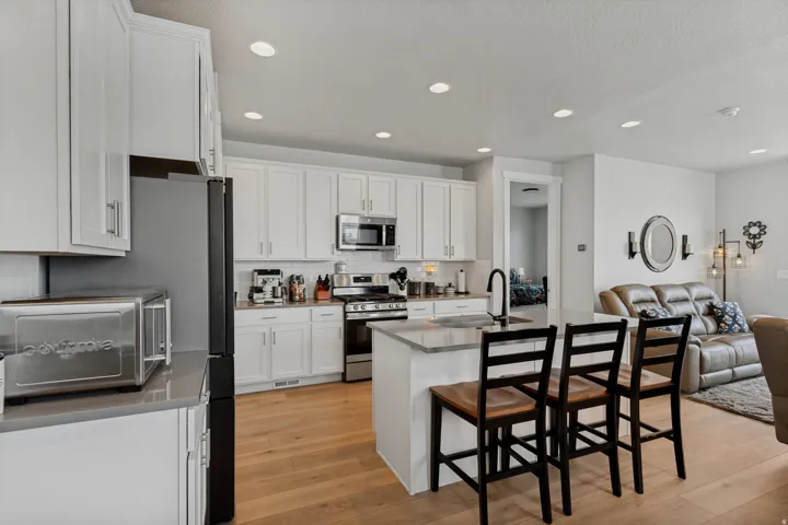 Kitchen featuring white shaker cabinetry, stainless steel appliances, wood-finish flooring, and recessed lighting