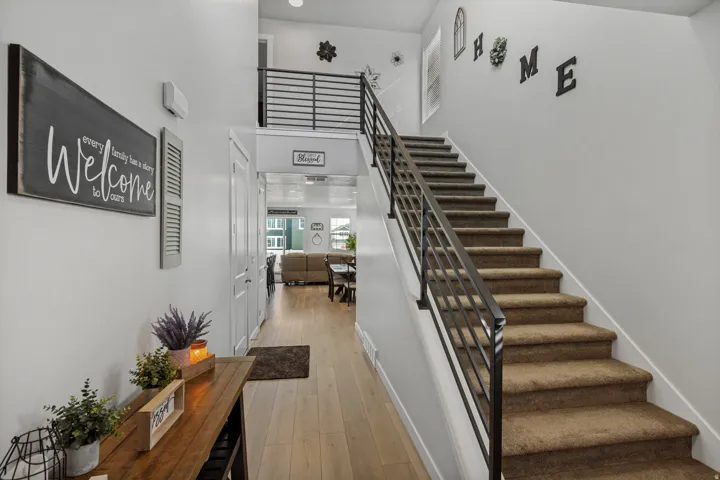 Entryway featuring wood-finish flooring and a carpeted staircase with a black metal railing