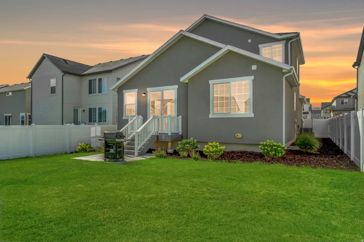 Expansive lawn with a vinyl privacy fence, rear concrete patio, and mature landscaping