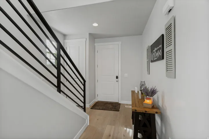 Light wood-finish flooring, white walls, and a contemporary black metal stair railing