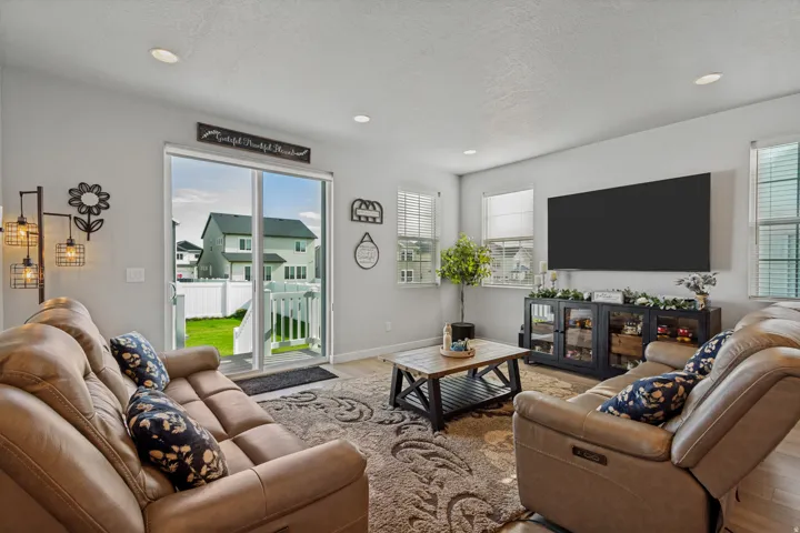 Recessed lighting, multiple windows with blinds, sliding glass patio door, and wood-finish flooring