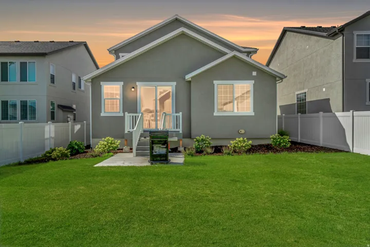 Expansive backyard featuring a manicured lawn, a concrete patio, and a white privacy fence