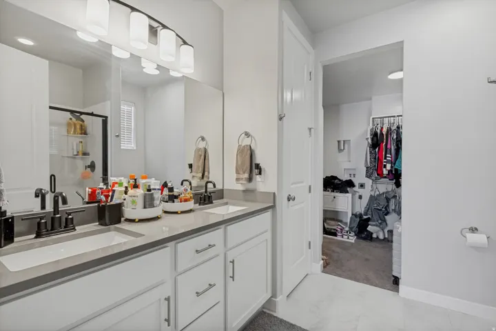 Dual vanity with matte black fixtures, integrated sinks, and ample storage cabinetry